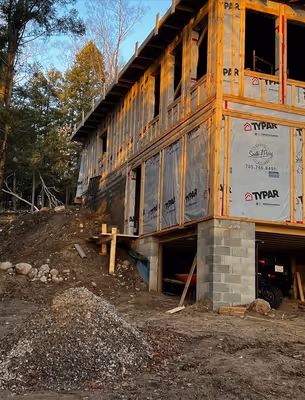 Close-up exterior view of a wooden house frame under construction, showing the intricate network of beams and supports.